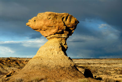 Hoodoo on field against cloudy sky