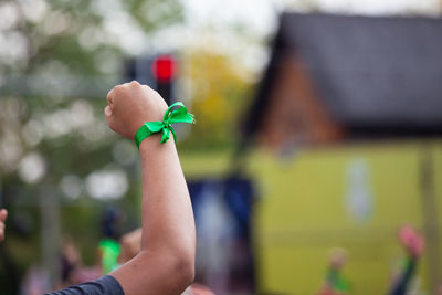 Cropped hand with green ribbon at concert