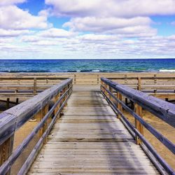 Boardwalk leading towards sea against sky