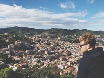 Young man looking at townscape against sky