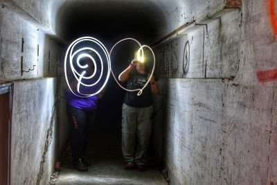 Full length of female friends light painting at corridor