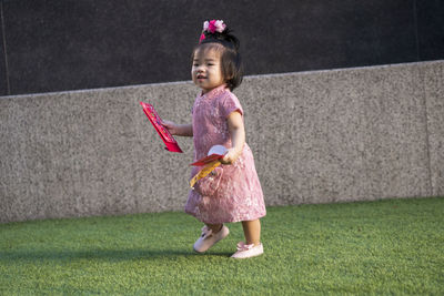 Girl holding umbrella while standing on grass