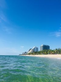 Scenic view of sea by buildings against clear blue sky