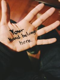 Close-up of hand holding text on wall
