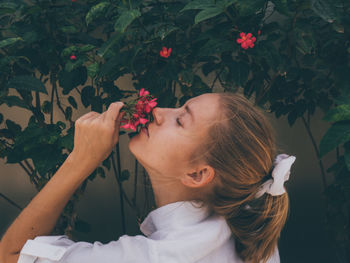 Portrait of woman with pink flowers against plants