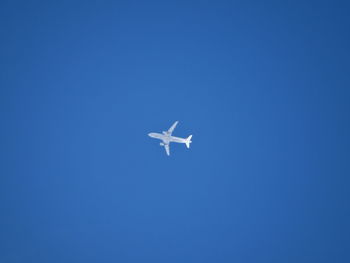 Low angle view of airplane against clear blue sky