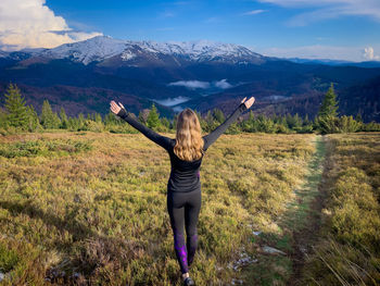 Rear view of fit woman with her arms outstretched enjoying the beautiful snowcapped mountains around