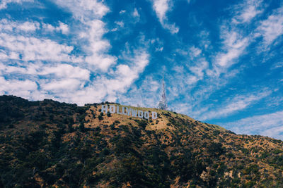 Low angle view of text on hill against sky