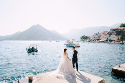 Couple kissing on mountain by lake against sky