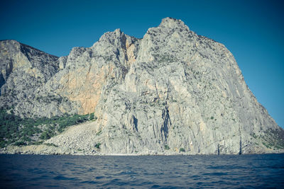 Scenic view of sea and mountains against clear blue sky