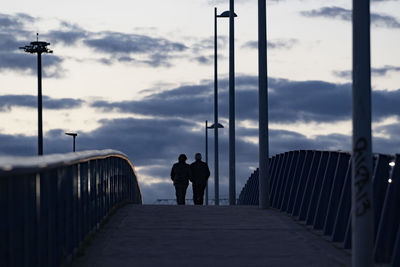 Rear view of people walking on bridge