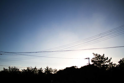 Low angle view of silhouette vapor trail against sky