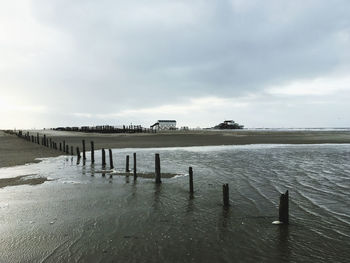 Wooden posts in sea against sky