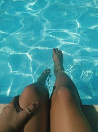 Low section of woman relaxing by swimming pool