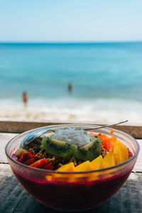 Close-up of fruits in bowl on table against sea