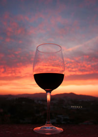 Close-up of wineglass against orange sky