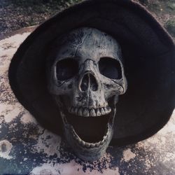 Close-up of human skull with hat on floor outdoors