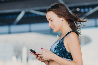 Side view of young woman using mobile phone