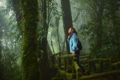 Woman standing by trees in forest