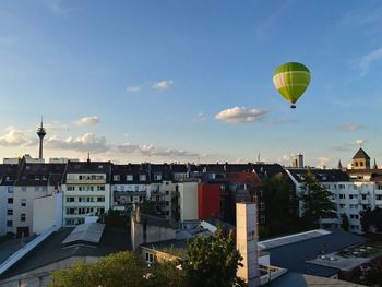 Hot air balloons flying in city against sky