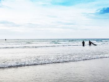 People standing on beach against sky