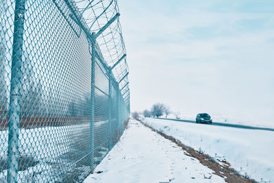 Snow covered fence against sky