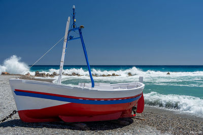 Boat moored on beach against clear sky