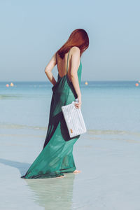 Woman standing at beach against clear sky