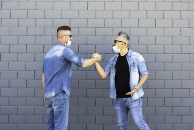 Men holding hands while standing against wall