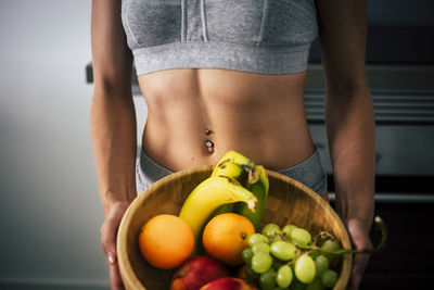 Midsection of woman holding fruits in basket