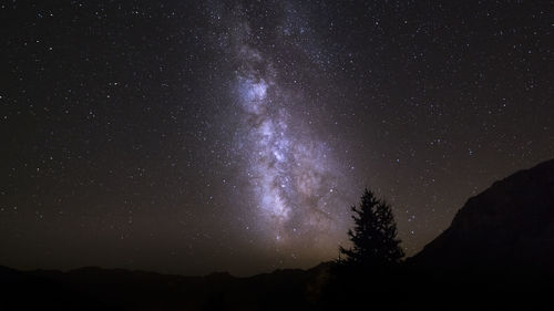 Low angle view of silhouette mountain against star field