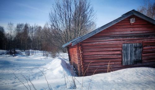 Snow covered bare trees and building against sky