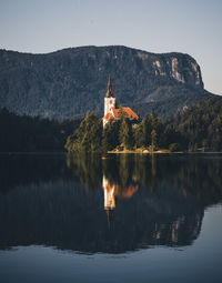 Reflection of trees on lake by mountain against sky