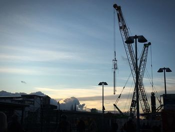 Silhouette of cranes against sky