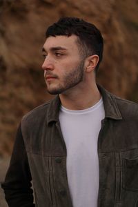 Close-up of young man looking away against wall