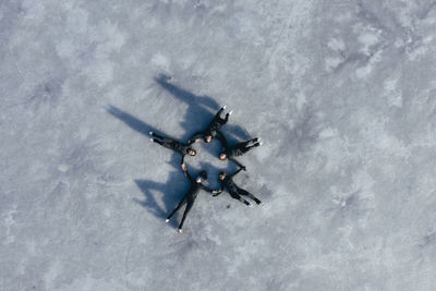 Aerial view of group of female ice-skaters lying together on surface of frozen lake