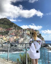 Rear view of woman standing by railing against sky