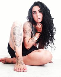 Portrait of woman with tattoo sitting against white background