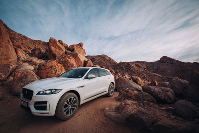 Car on rock formation against sky