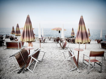 Lounge chairs and parasols on beach against sky