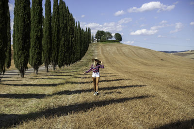 Full length of woman walking on field against sky