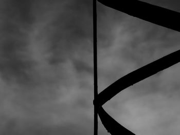 Low angle view of metal structure against cloudy sky