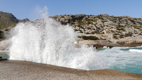 Scenic view of crashing wave  against clear sky