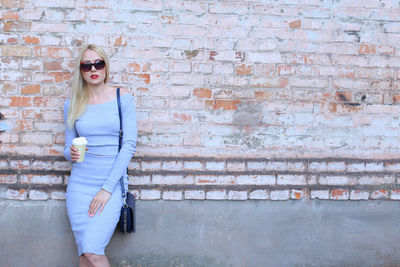 Portrait of young woman standing against wall