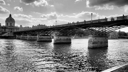 Bridge over river against cloudy sky