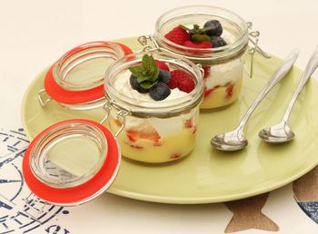 Fruits and yogurts in jars on table