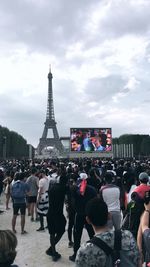 Group of people in front of tower against cloudy sky