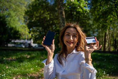 Young woman using mobile phone while sitting on field