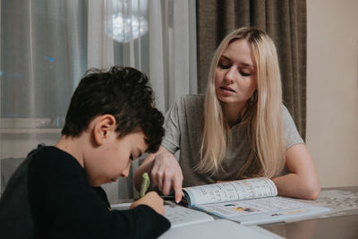 Mom and son are doing homework. sister helps brother solve math. home schooling. high quality photo