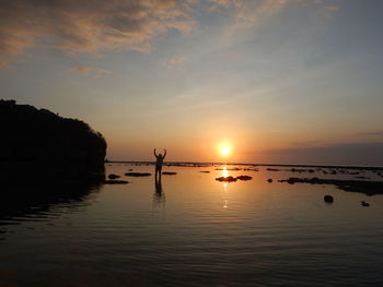 Silhouette of man in sea during sunset